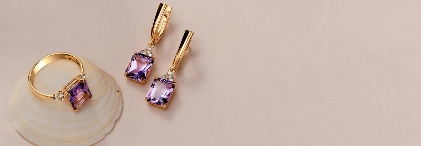 Gold ring and earrings set with purple gemstones and diamonds on a soft beige background