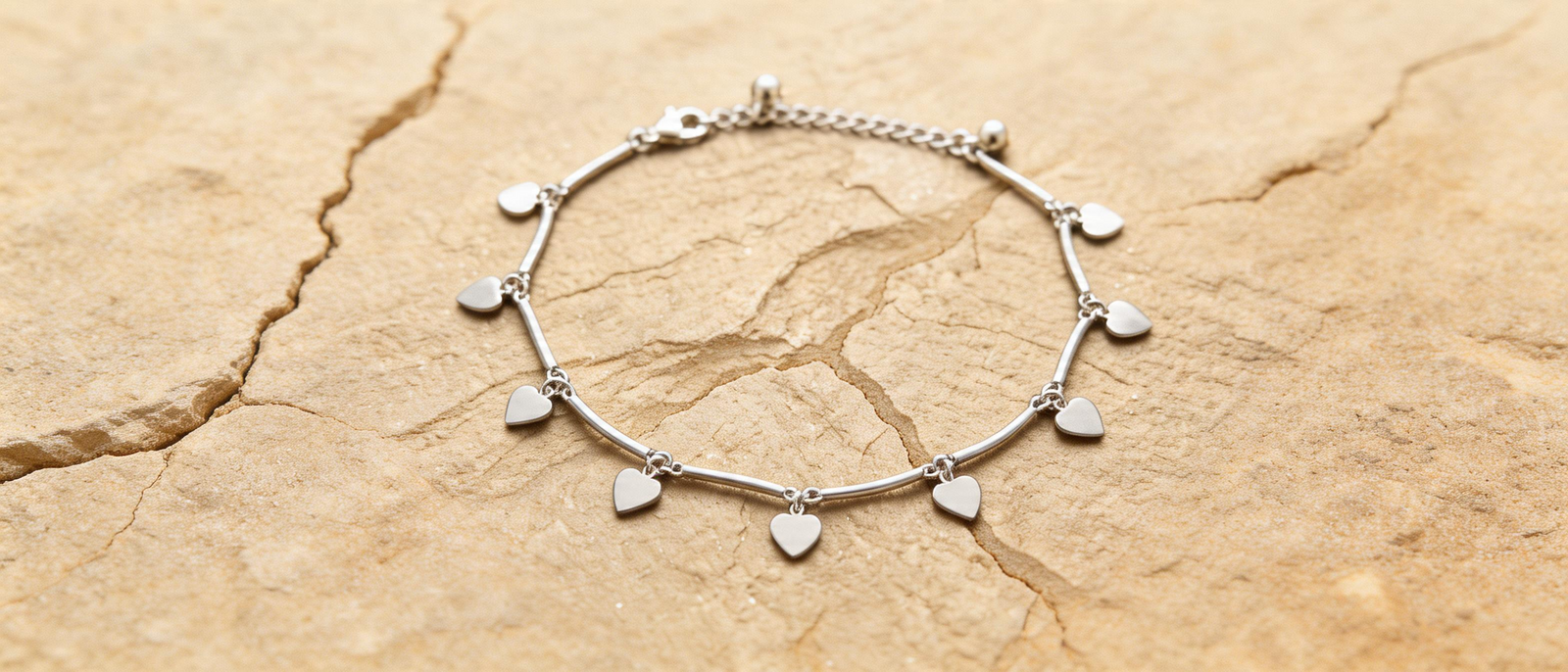 Silver anklet with leaf charms and round pendant on white background