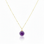 Necklace with a purple bead pendant on a gold chain against a white background