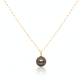 Gold necklace with a dark pearl pendant on a white background