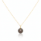 Gold necklace with a dark pearl pendant on a white background