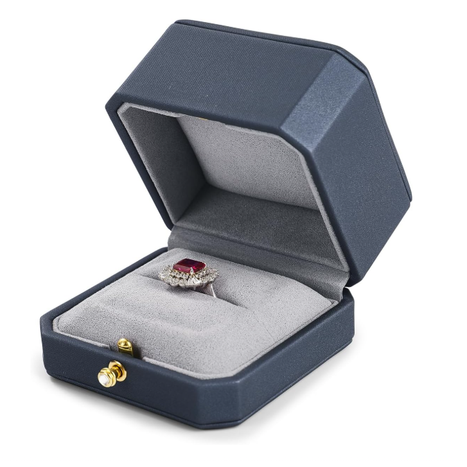 Blue jewelry box with a ring featuring a red gemstone on a white background