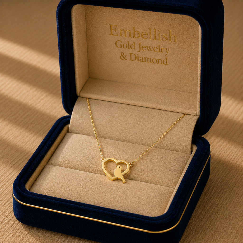 Gold necklace with a heart and bird design in an 'Embellish Gold Jewelry & Diamond' box.