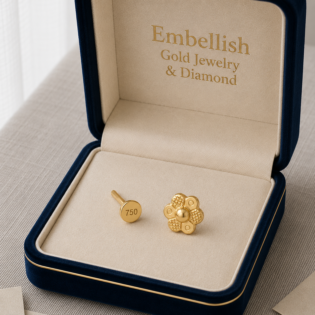 Gold earrings in a 'Embellish Gold Jewelry & Diamond' box on a light background