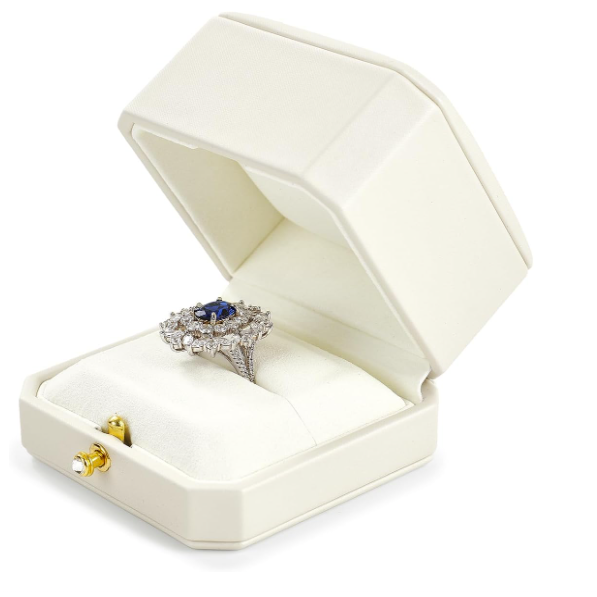 Silver ring with blue gemstone in an open cream jewelry box on a white background