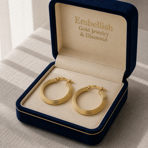 Gold hoop earrings in a 'Embellish Gold Jewelry & Diamond' box on a striped fabric background