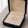 Gold ring in a 'Embellish Gold Jewelry & Diamond' box on a neutral background