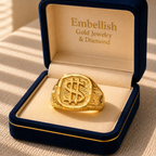 Gold ring with dollar sign design in a 'Embellish Gold Jewelry & Diamond' box.