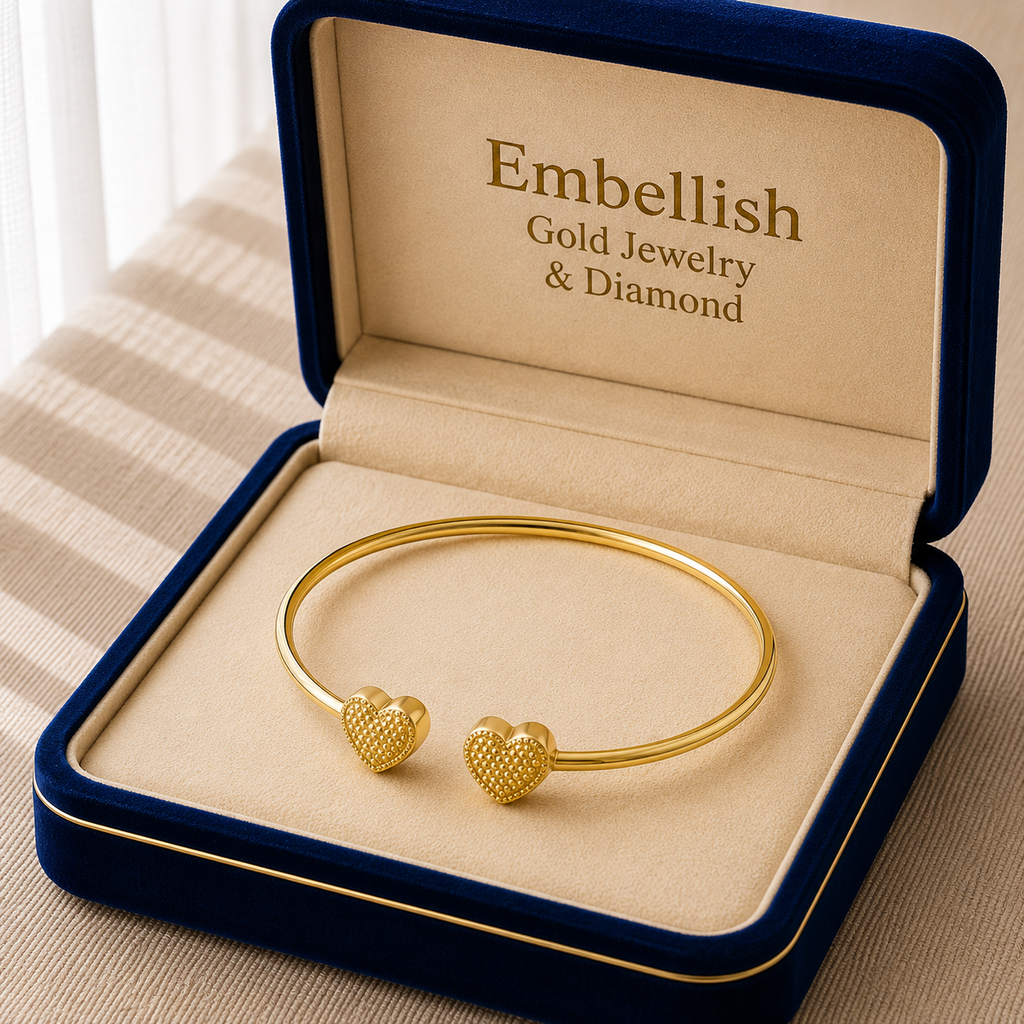 Gold bracelet with heart-shaped ends in a 'Embellish' jewelry box.