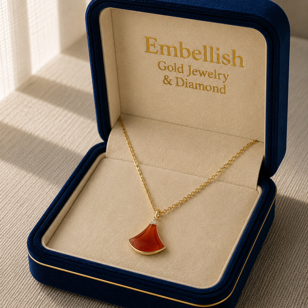 Gold necklace with a red pendant in an 'Embellish' jewelry box.