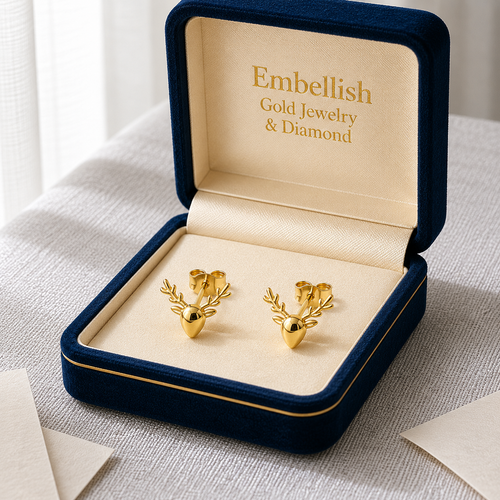 Gold deer-shaped earrings in a 'Embellish Gold Jewelry & Diamond' box on a textured surface.