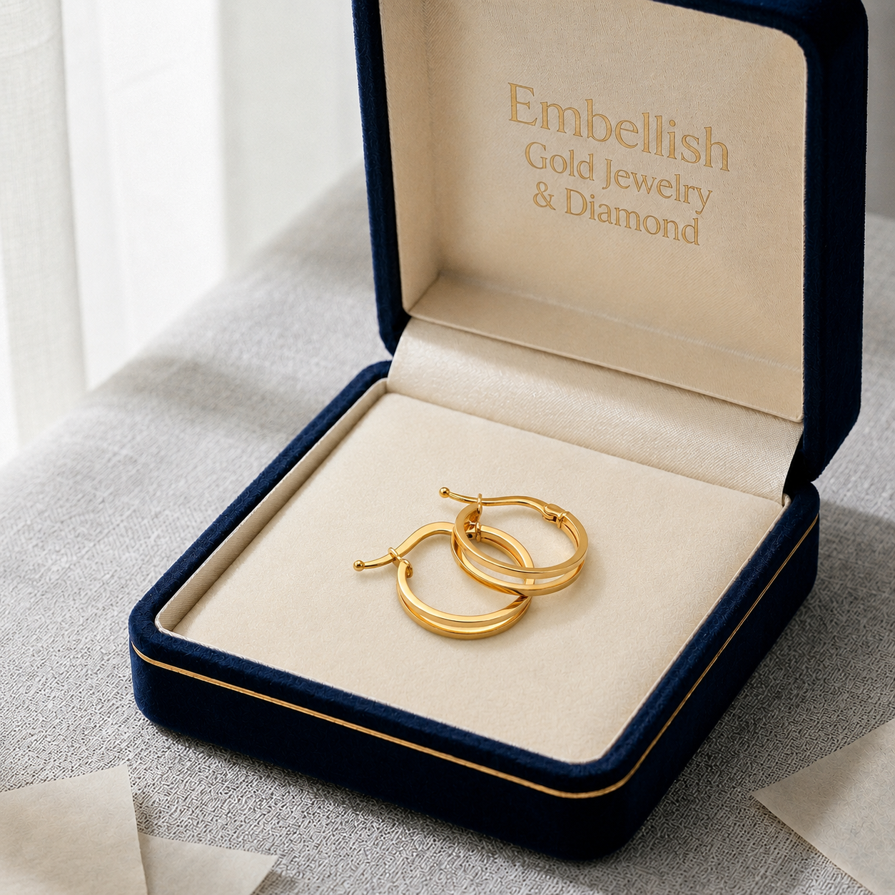 Gold hoop earrings in a 'Embellish Gold Jewelry & Diamond' box on a light background
