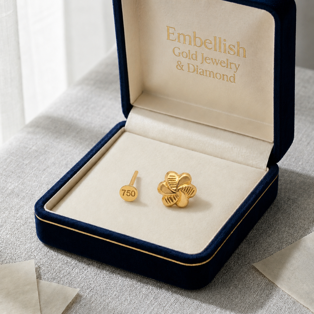 Gold earrings in a 'Embellish Gold Jewelry & Diamond' box on a light background