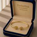 Gold bracelet in a 'Embellish Gold Jewelry & Diamond' box on a wooden surface.