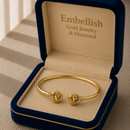 Gold bracelet in a 'Embellish Gold Jewelry & Diamond' box on a wooden surface.