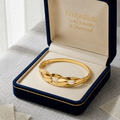 Gold bracelet in a 'Embellish Gold Jewelry & Diamond' box on a light gray surface