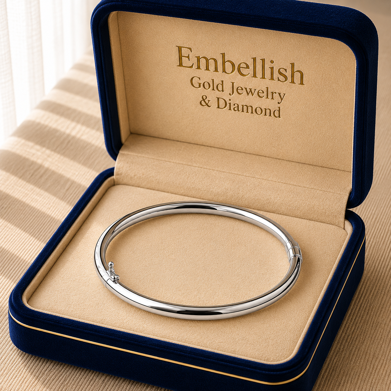 Silver bracelet in a 'Embellish Gold Jewelry & Diamond' box on a beige surface.