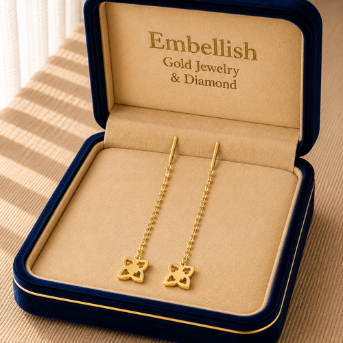 Gold earrings in a 'Embellish' jewelry box on a striped fabric background