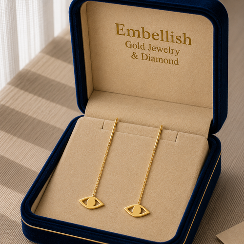 Gold earrings in a 'Embellish Gold Jewelry & Diamond' box on a striped surface.