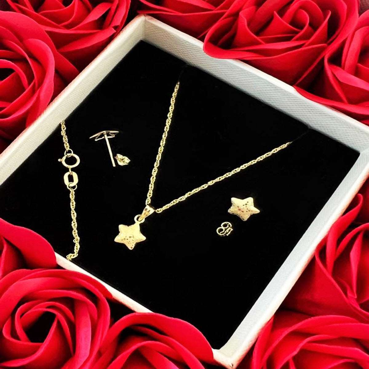 Gold star jewelry set including necklace, earrings, and bracelet in gift box with red roses