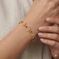 Gold chain bracelet on a wrist with a neutral background