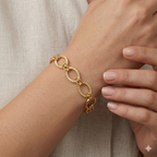 Gold chain bracelet on a wrist with a neutral background