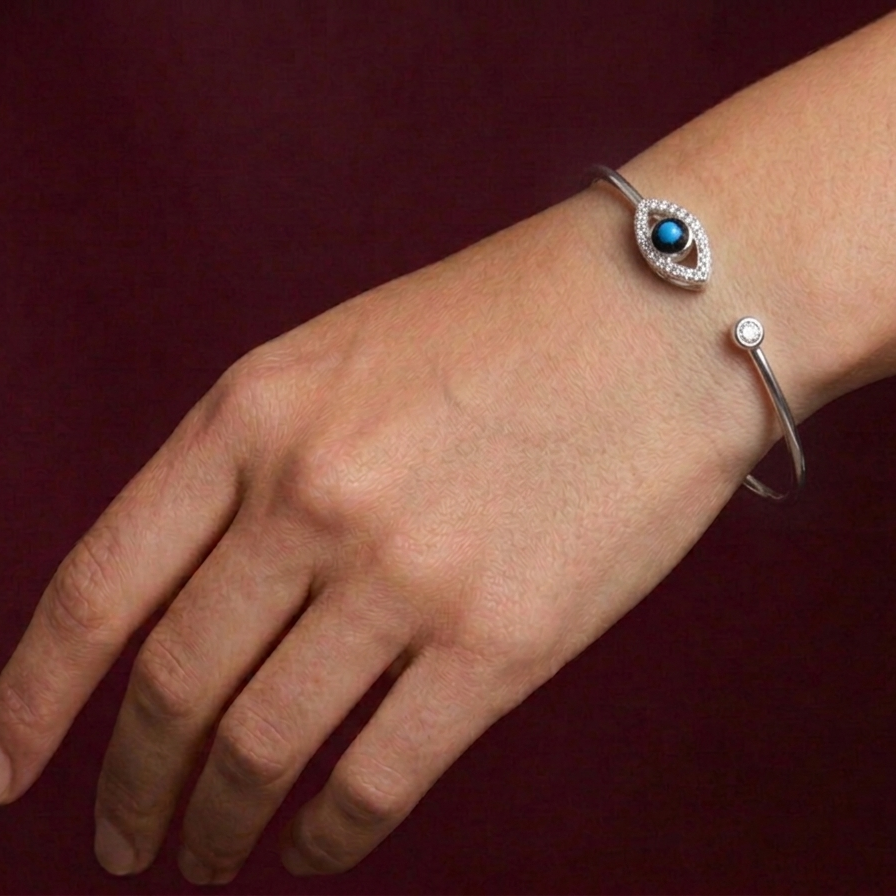 Silver bracelet with a blue gemstone on a wrist against a dark background