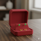 Gold earrings with green gemstones in a red jewelry box on a wooden table
