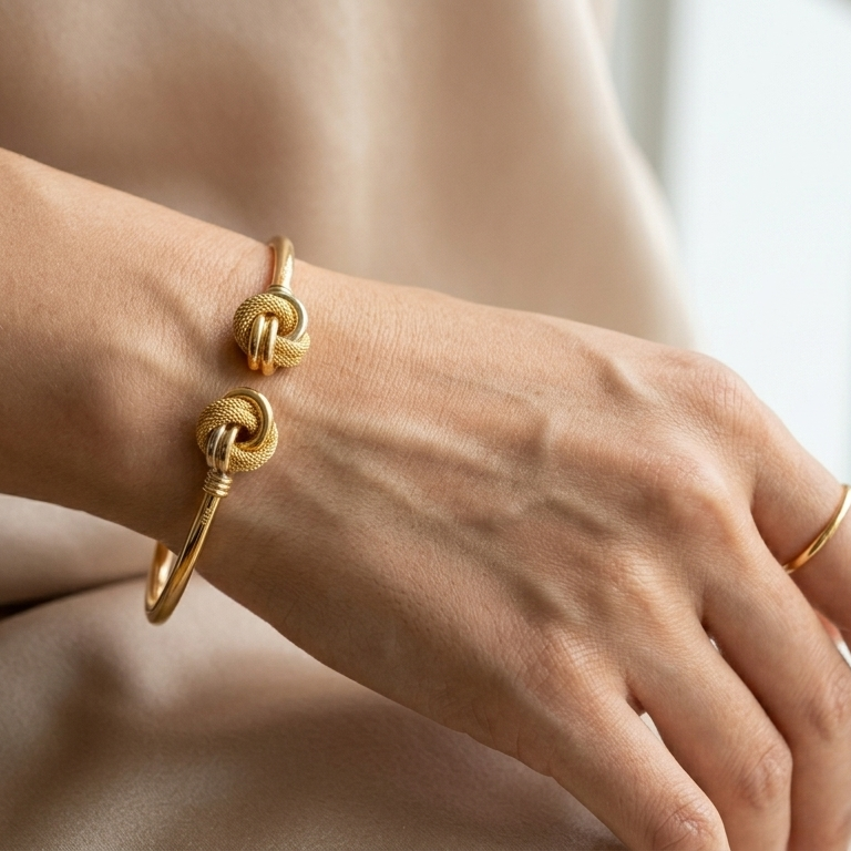 Gold bracelet on a person's wrist with a neutral background