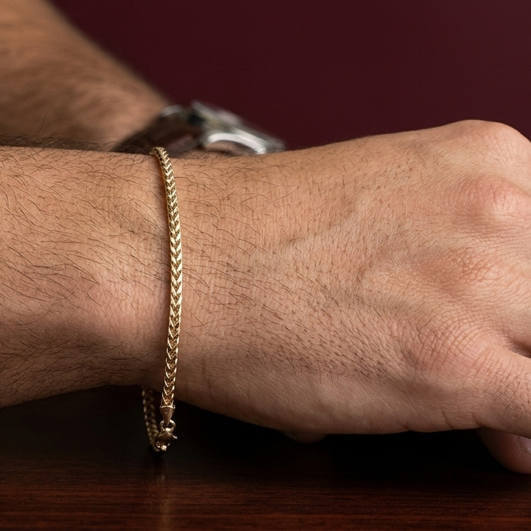 Close-up of a wrist wearing a gold bracelet on a wooden surface.