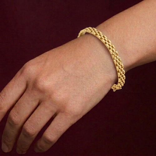 Gold bracelet on a wrist against a dark background