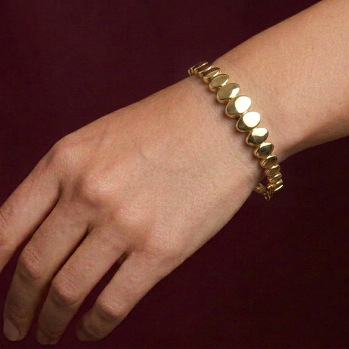 Bracelet with emerald and diamond accents on a wrist against a dark background