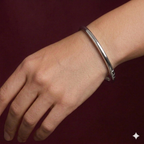 Silver bracelet on a wrist against a dark red background