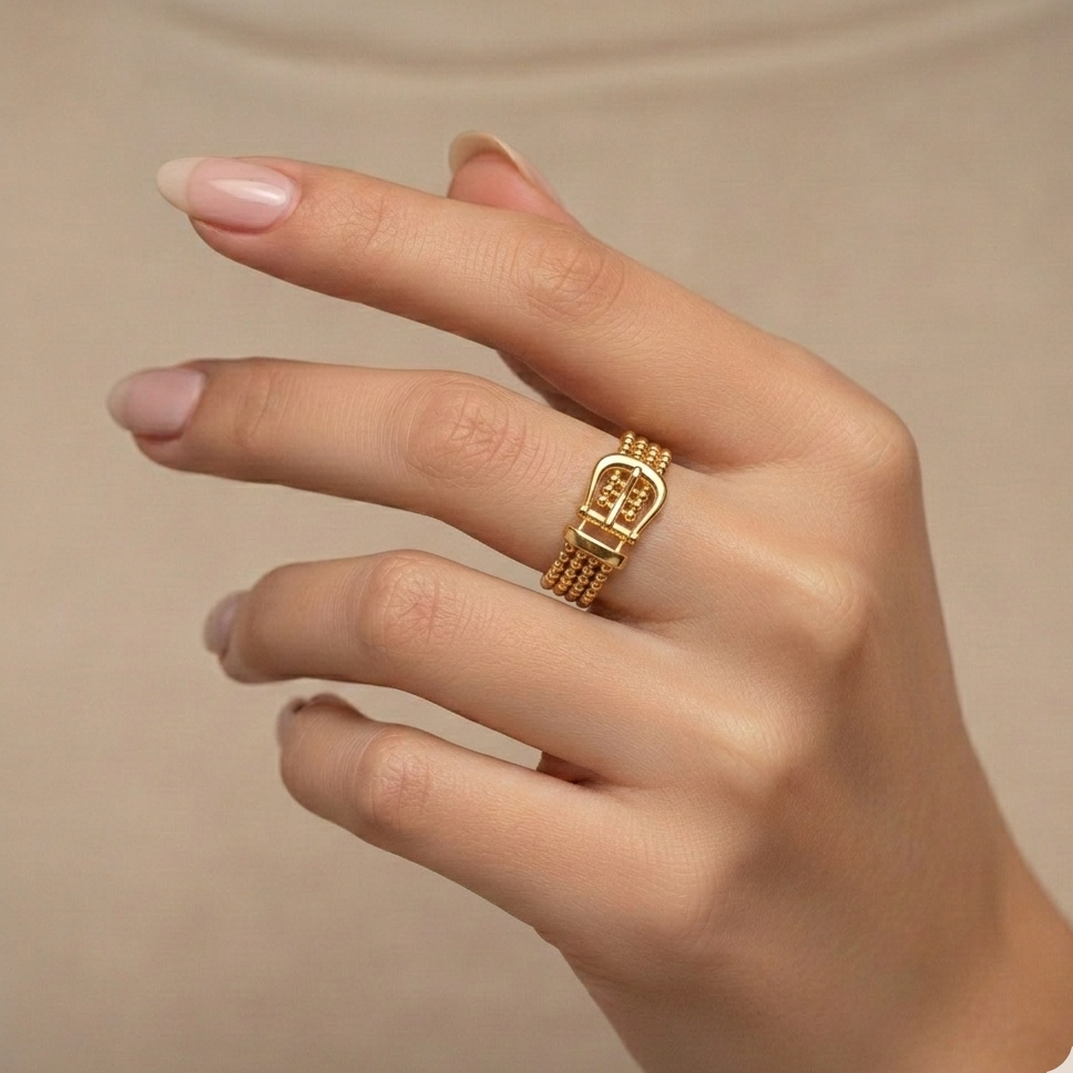 Hand wearing a gold heart-shaped ring on a beige background