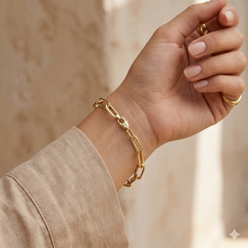 Gold chain bracelet on a wrist with a neutral background
