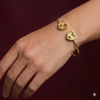 Gold bracelet with heart-shaped ends on a wrist against a dark red background