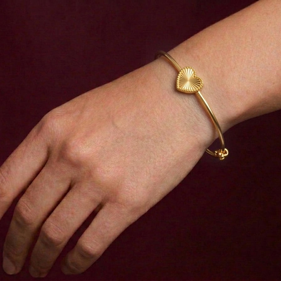 Gold butterfly bracelet on a wrist against a dark background