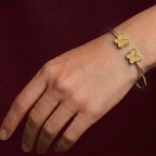 Gold butterfly bracelet on a wrist against a dark background
