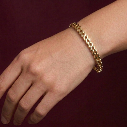 Gold bracelet on a wrist against a dark background