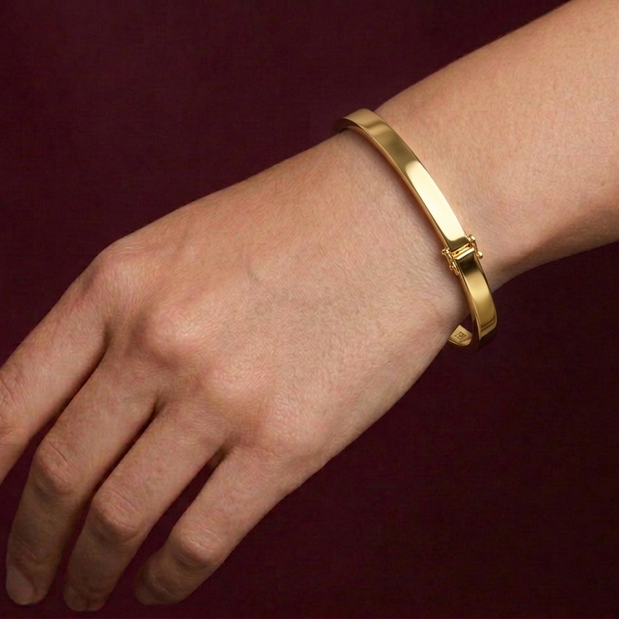 Gold bracelet on a wrist against a dark background