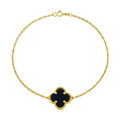 Gold bracelet with a black clover-shaped charm on a white background