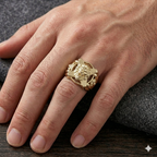 Gold ring with a lion design on a person's finger against a dark background