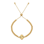 Gold beaded bracelet with a clover-shaped charm on a white background