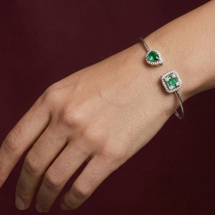 Bracelet with emerald and diamond accents on a wrist against a dark background