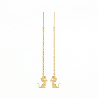 Gold cat-shaped earrings on thin chains against a white background