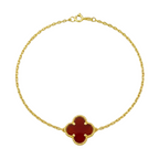 Gold bracelet with a red clover-shaped charm on a white background