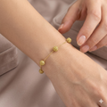 Gold bracelet on a wrist with a neutral background