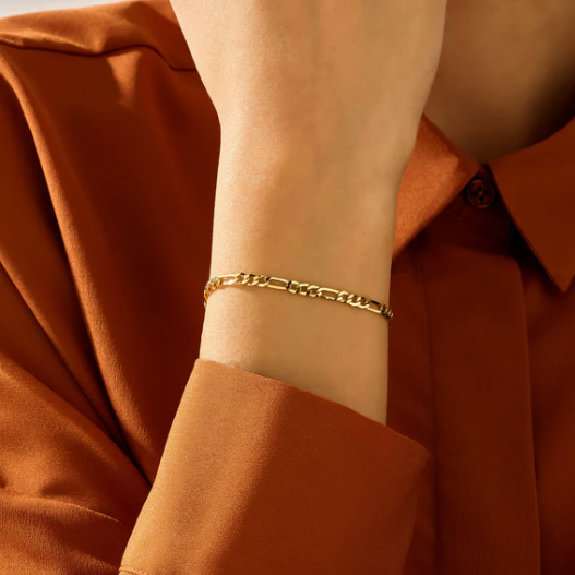 Gold bracelet on a wrist with a brown shirt background