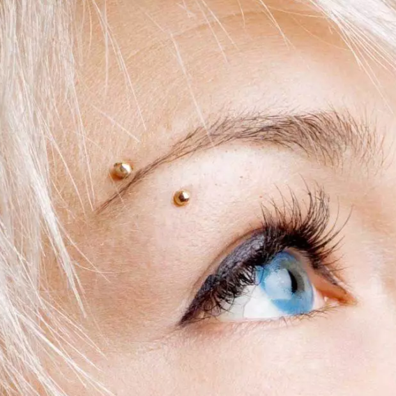 Close-up of a person with blonde hair and blue eyes wearing gold earrings.