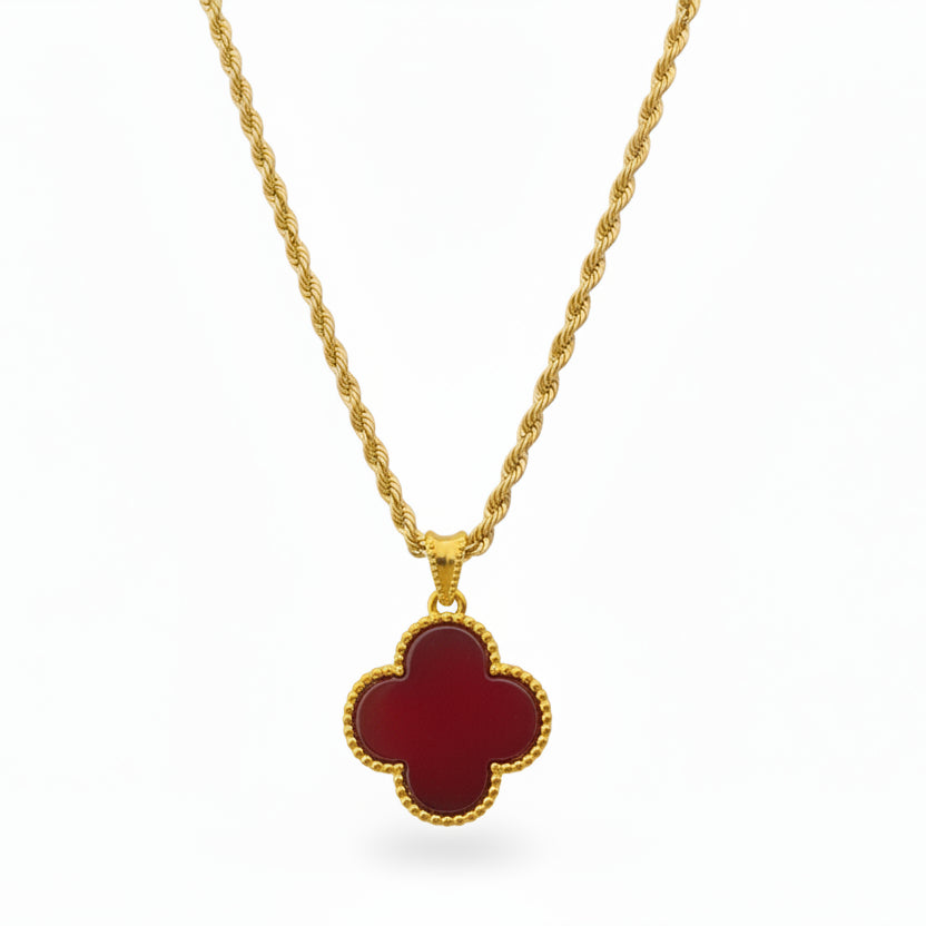Gold necklace with a red clover-shaped pendant on a white background